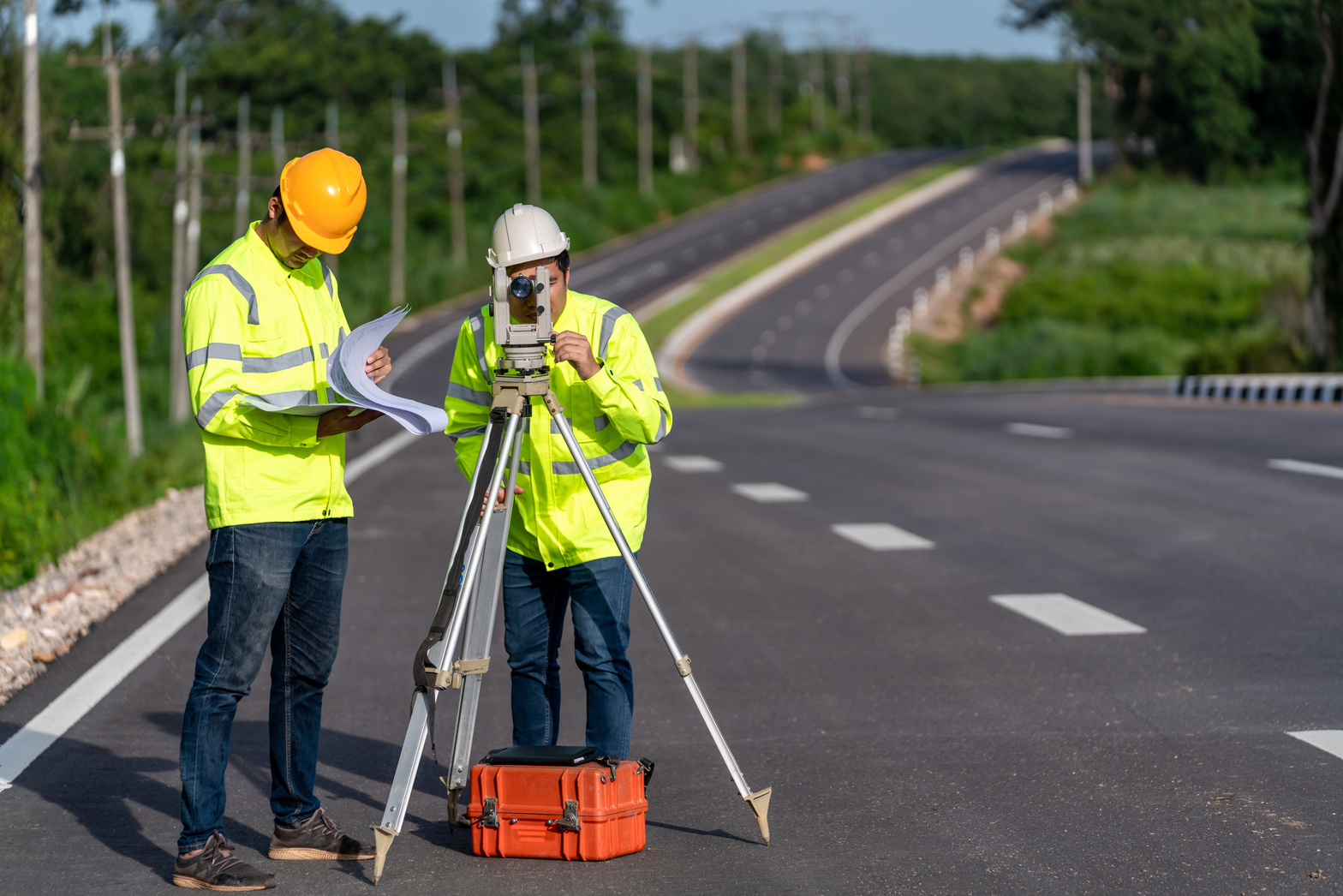 Asian survey engineers on road construction site use theodol